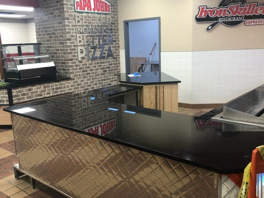 A counter in a pizza restaurant with a brick wall behind it.