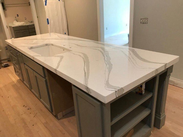A kitchen with a large white counter top and a sink.
