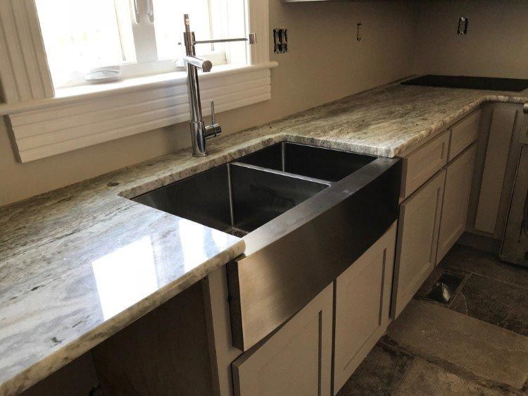 A kitchen with a stainless steel sink and granite counter tops