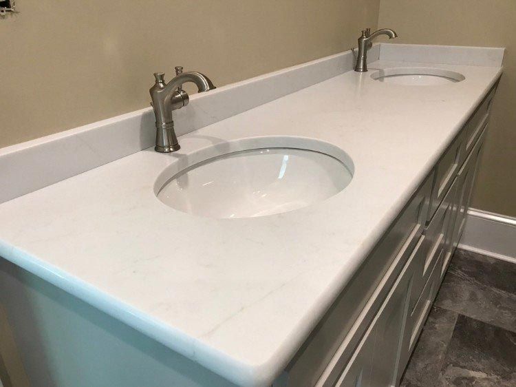 A bathroom vanity with two sinks and two faucets