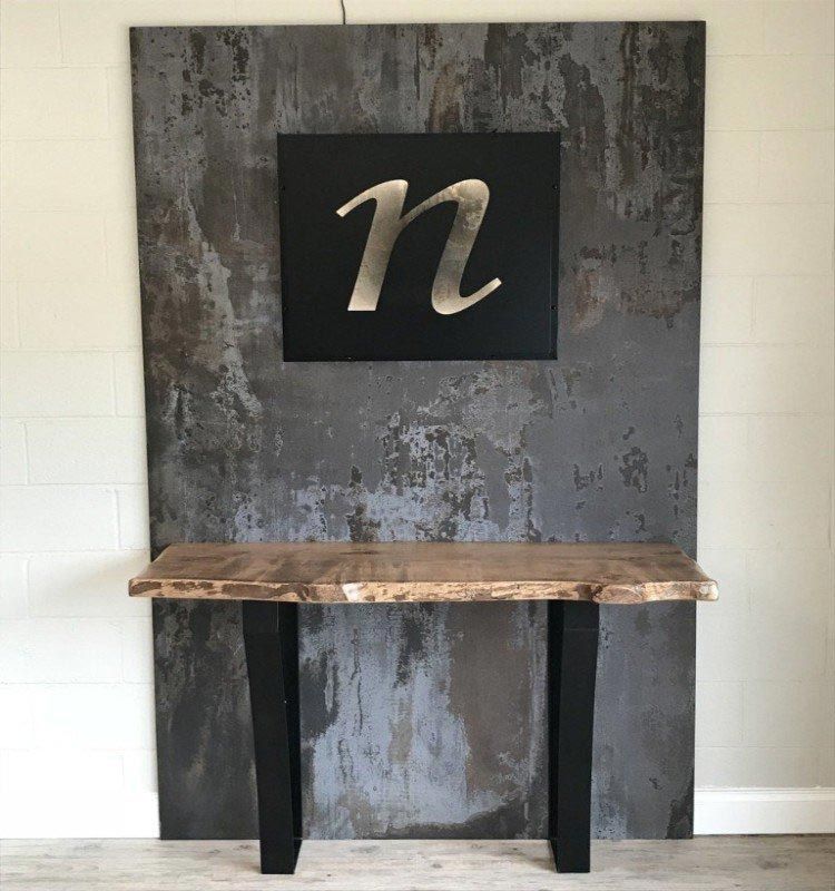 A wooden table in front of a wall with the letter n on it