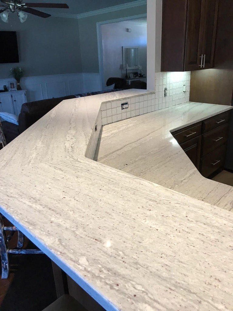 A kitchen with white granite counter tops and brown cabinets.