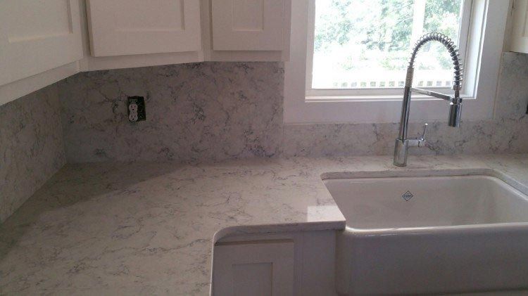 A kitchen sink with a faucet and a window in the background.