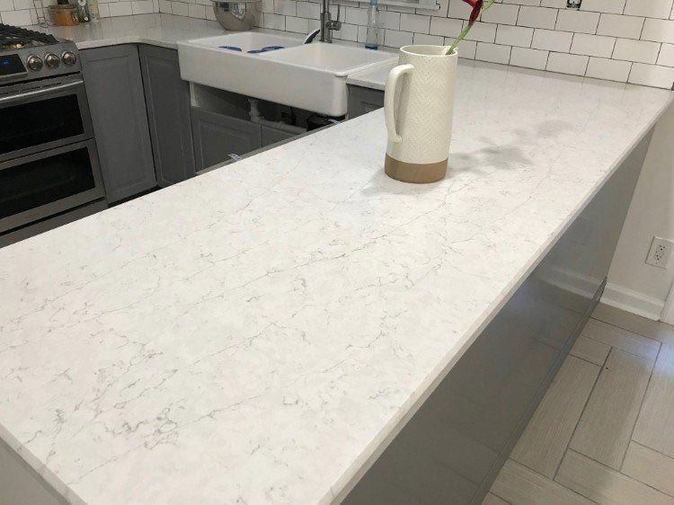 A white counter top in a kitchen with a pitcher on it.