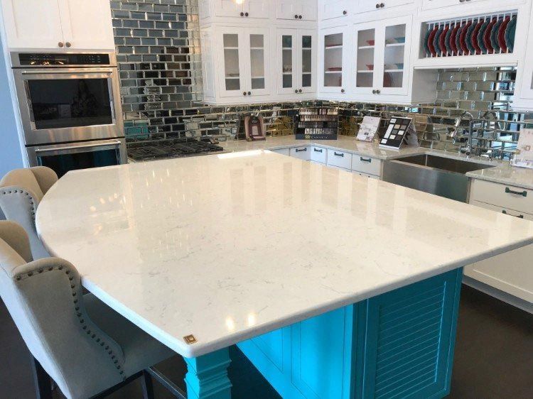 A kitchen with a large white counter top and a blue island.