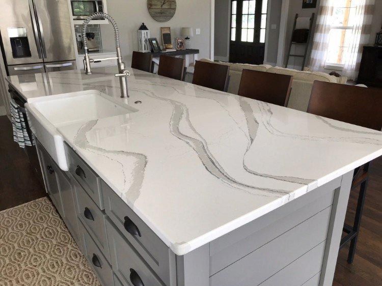 A kitchen with a large white counter top and a sink.