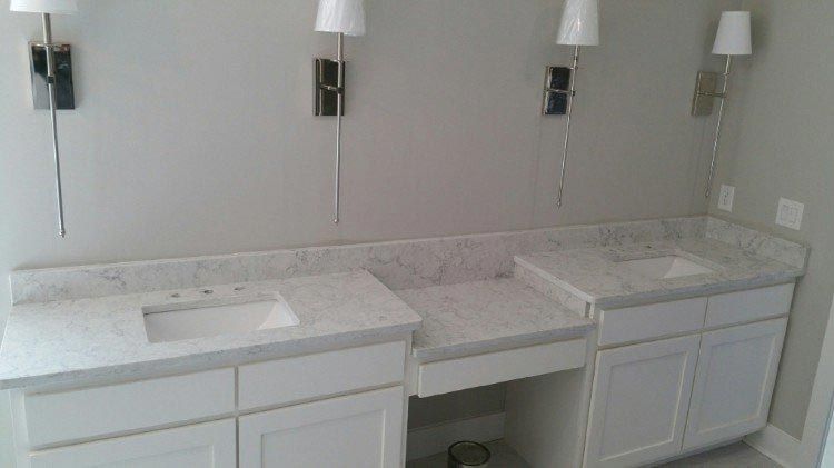 A bathroom with two sinks and two lamps on the wall.
