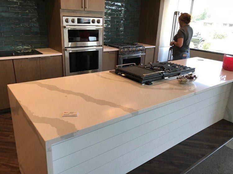 A woman is standing in a kitchen next to a large island.