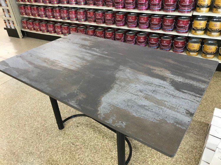 A table is sitting in front of a shelf of paint.