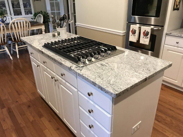 A kitchen with a large island with a stove top oven.