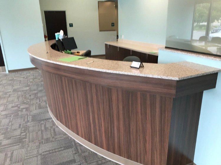 A curved wooden reception desk with a granite counter top