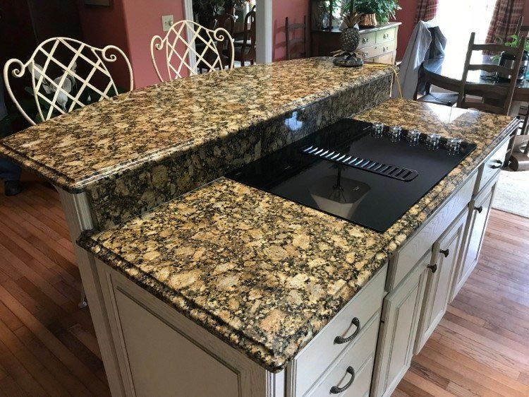 A kitchen island with granite counter tops and a stove top oven