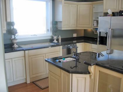 A kitchen with white cabinets and black counter tops