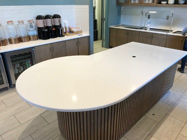 A kitchen with a large white table and wooden cabinets.