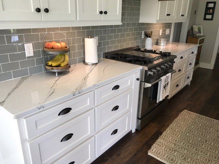 A kitchen with white cabinets , stainless steel appliances , and a stove.
