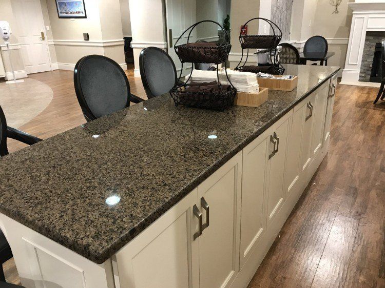 A kitchen with a large granite counter top and white cabinets
