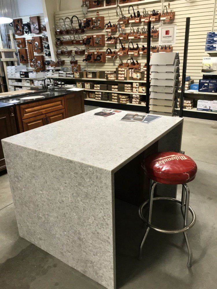 A kitchen island with a red stool in a store