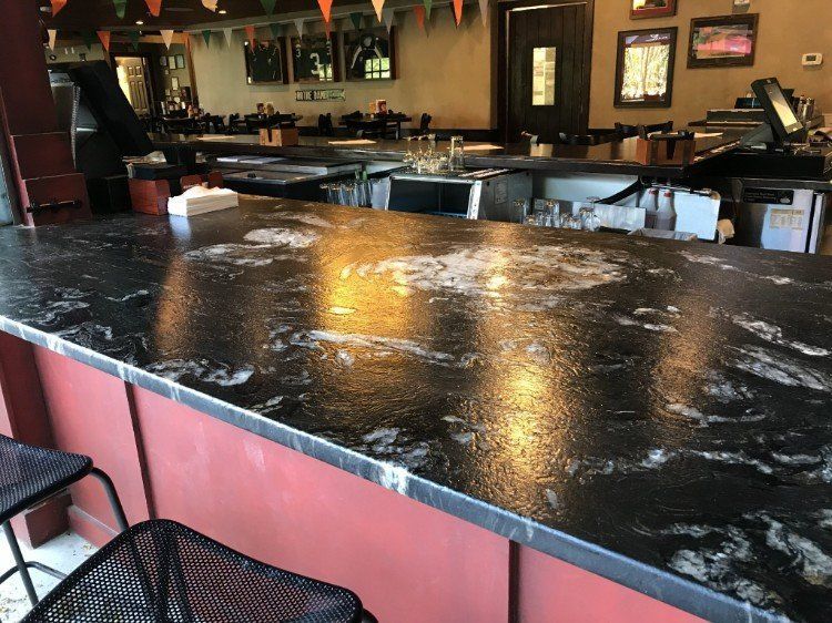 A bar in a restaurant with a black counter top