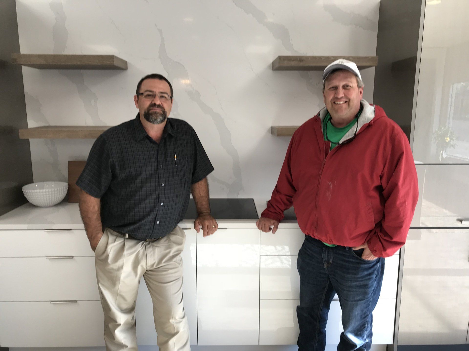 Two men are standing next to each other in a kitchen.