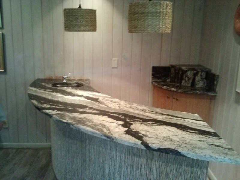 A kitchen with a marble counter top and a sink.