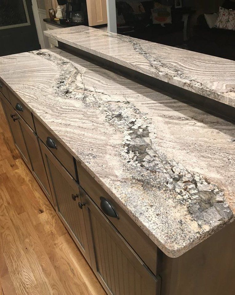 A kitchen counter with granite counter tops and gray cabinets.