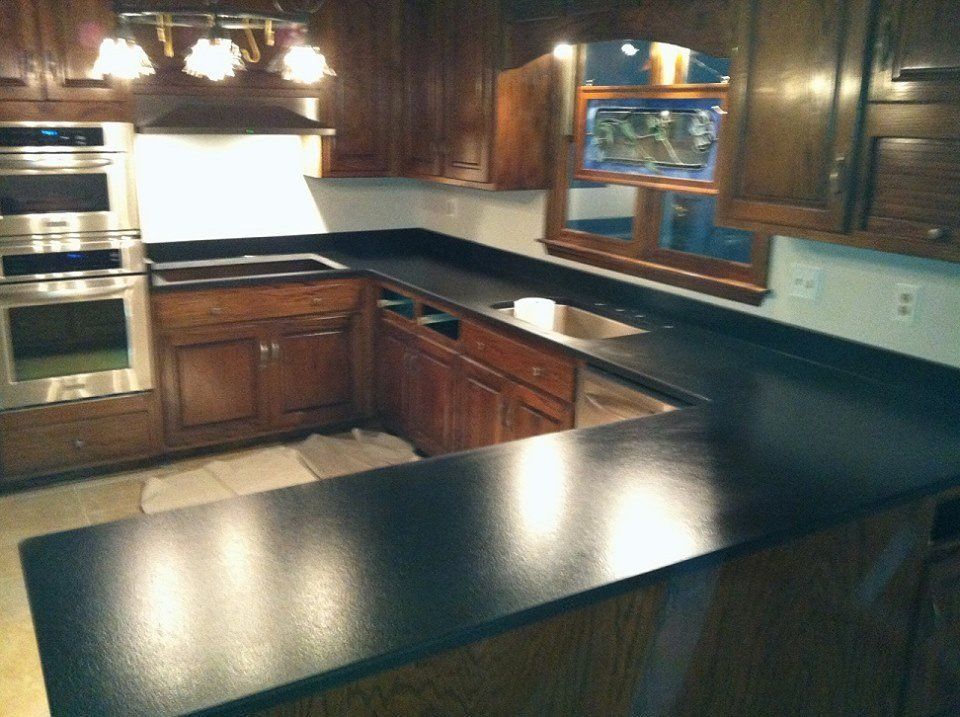A kitchen with black counter tops and wooden cabinets
