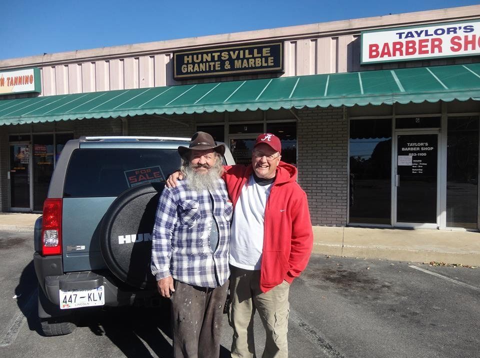 Two men standing in front of a building that says taylor 's barber shop