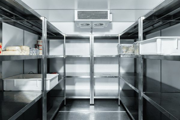 A walk-in commercial refrigerator with stainless steel shelving units containing food containers.