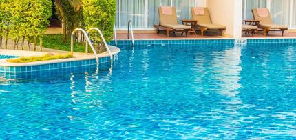 Swimming pool with clear blue water and lounge chairs on the patio.
