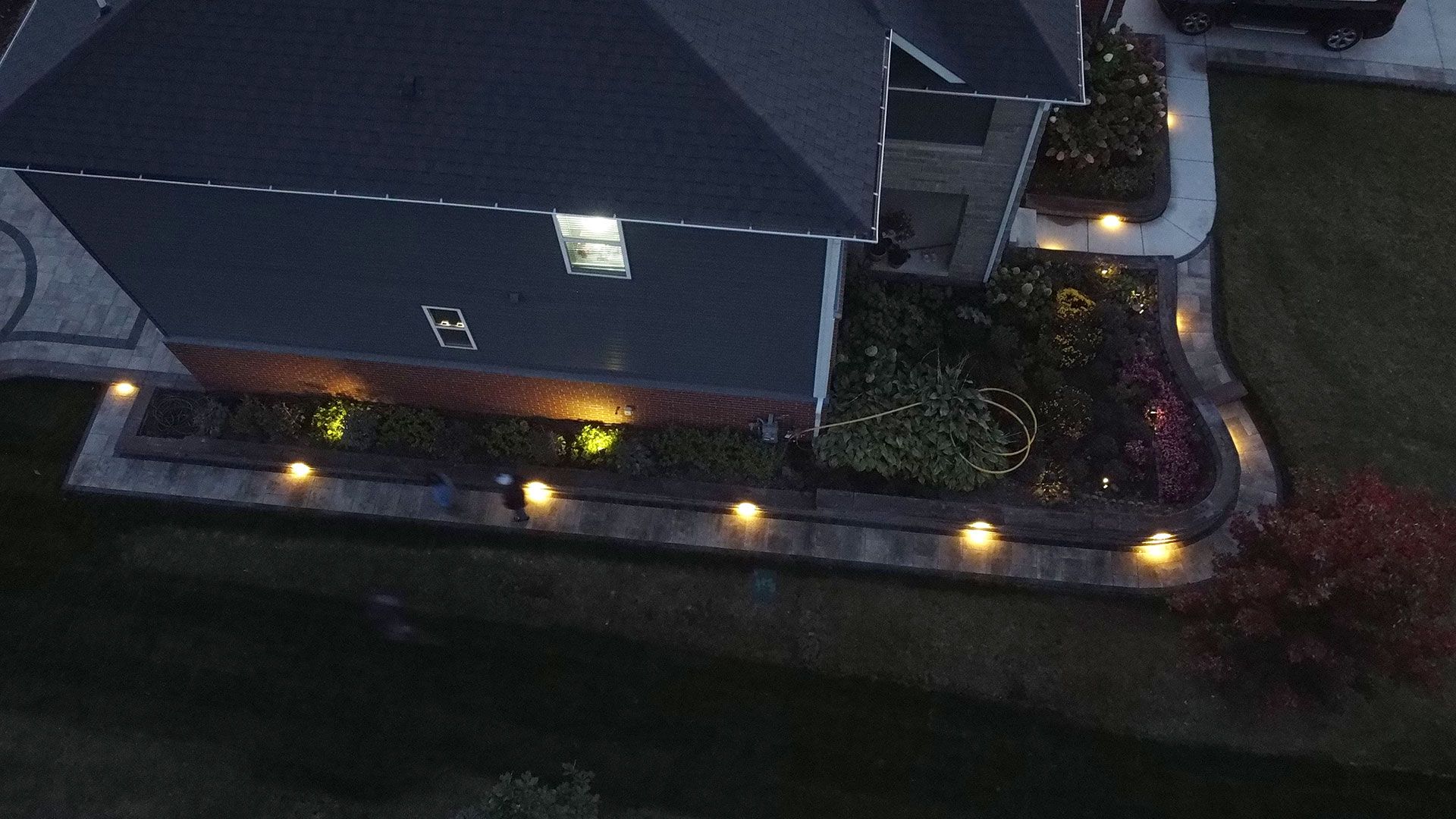 A house at dusk with landscape lighting illuminating the flower beds and walkway.