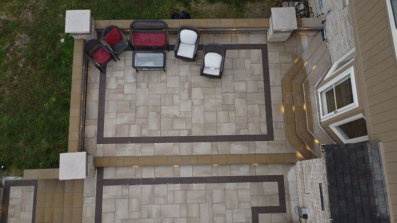 Overhead view of a paved patio with seating and a small table; adjacent to a building with windows.