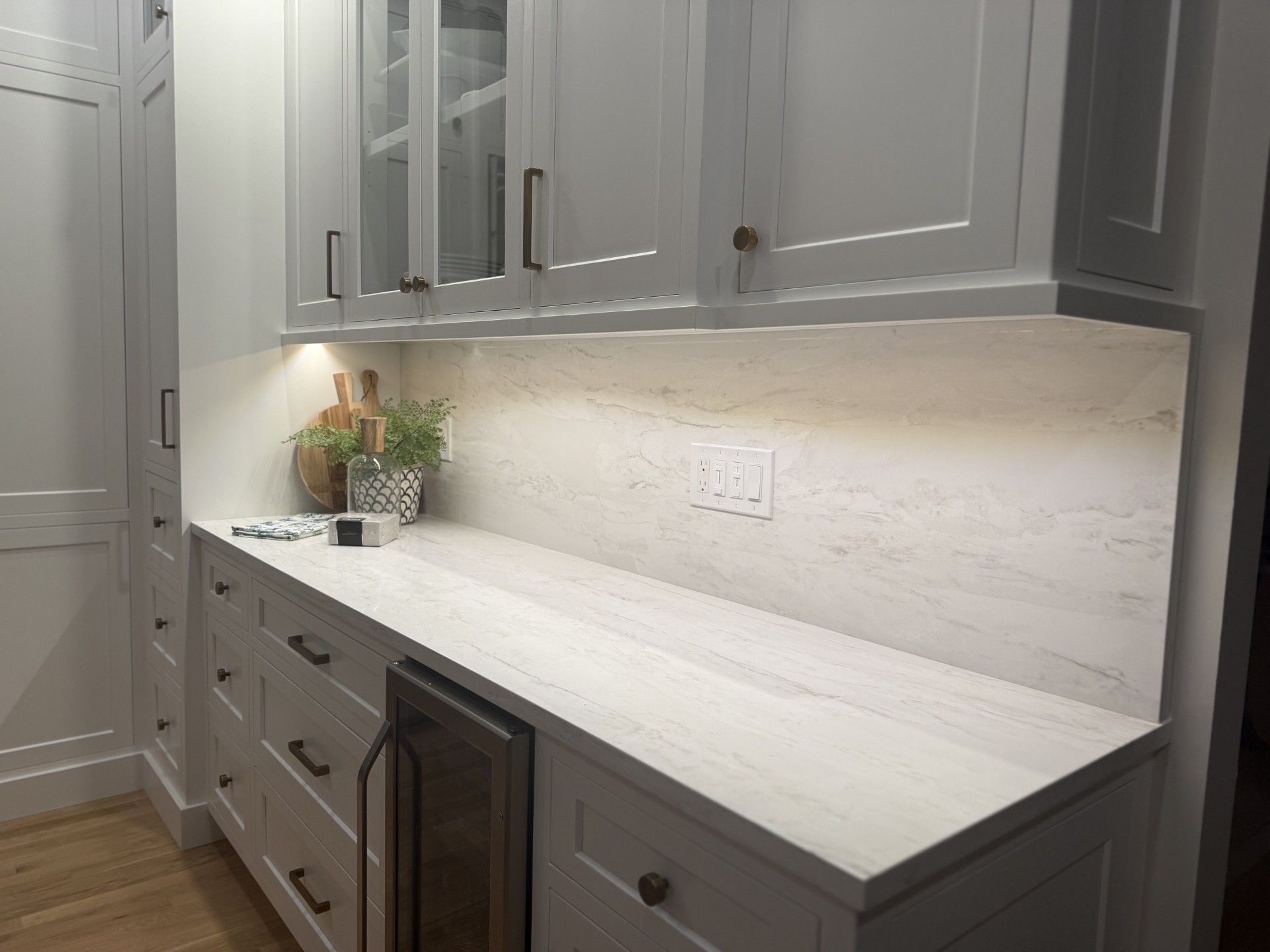 Modern gray kitchen with marble countertop, under-cabinet lighting, drawers, and built-in wine fridge