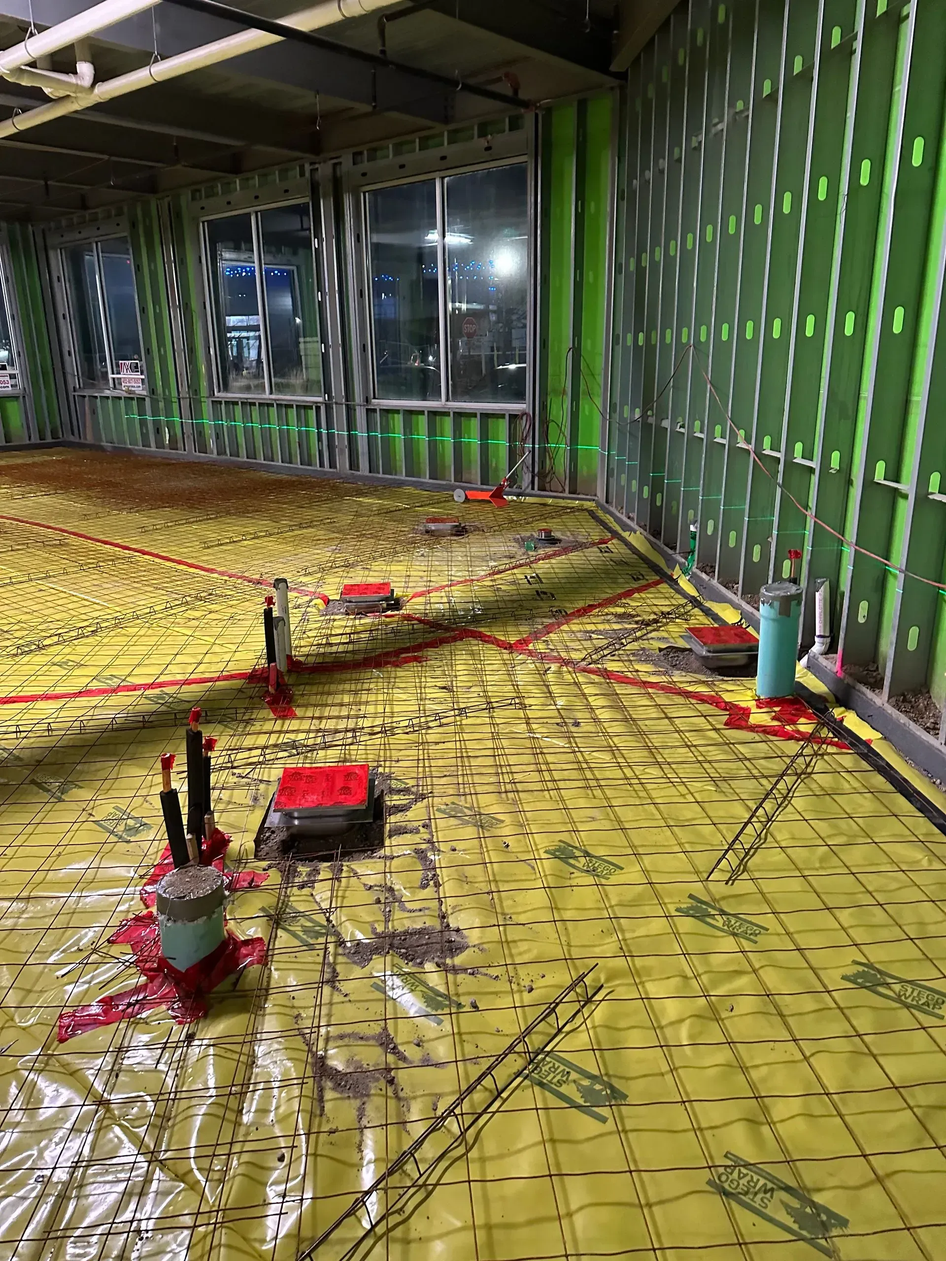 Construction site interior with yellow floor covering and green wall studs.