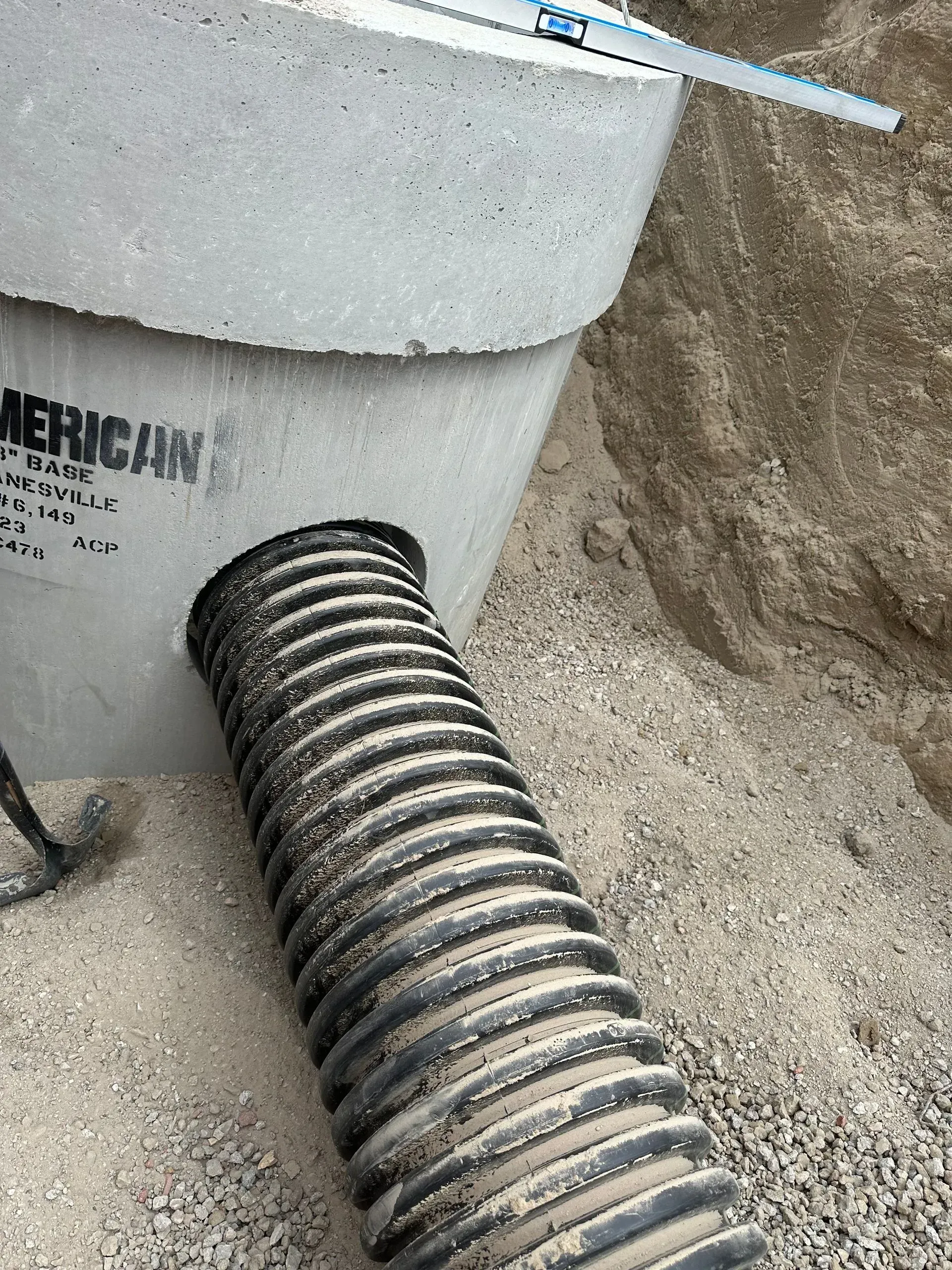 Gray concrete structure with corrugated black pipe, surrounded by gravel.