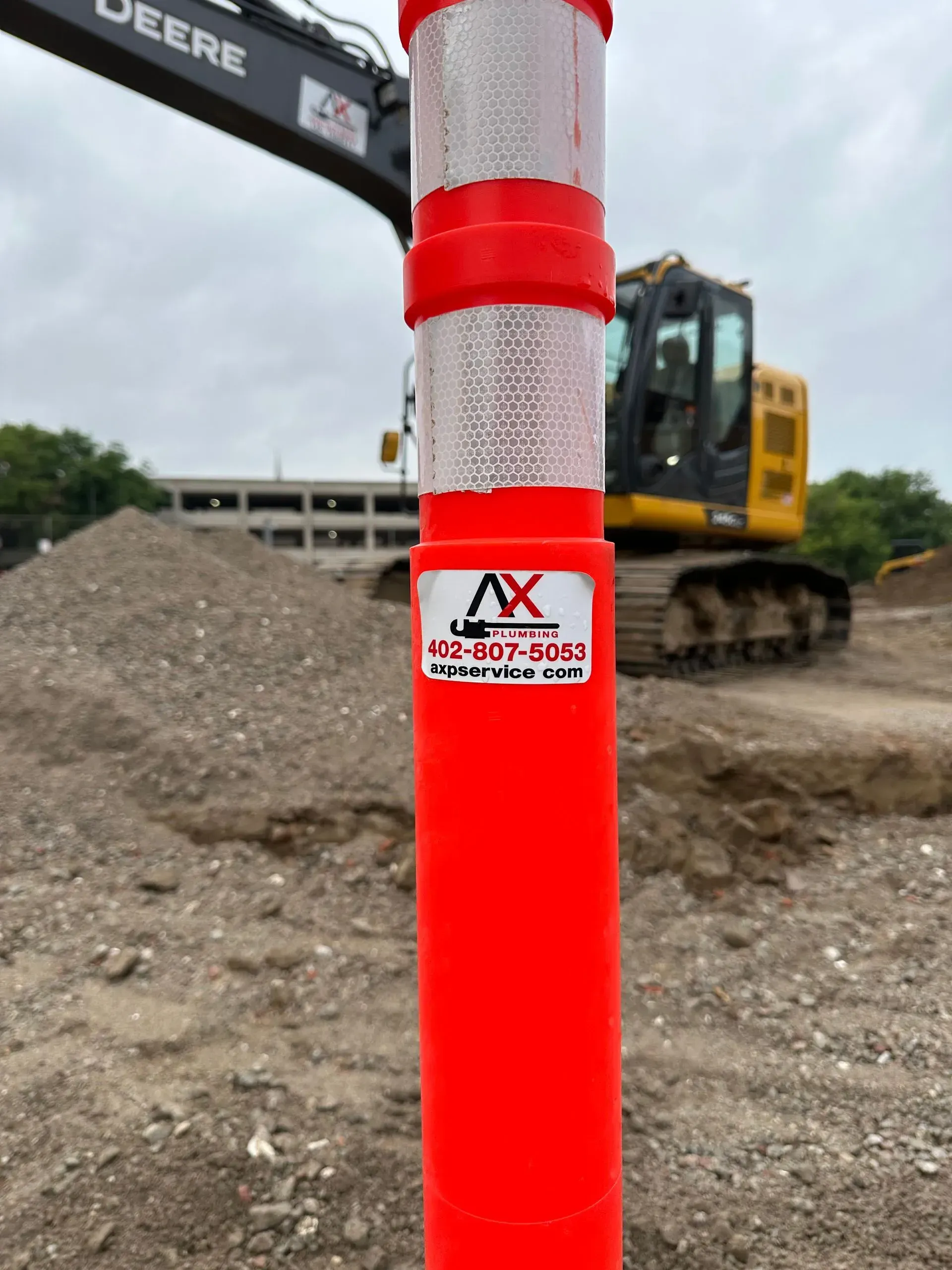 Bright orange reflective bollard with a construction site in the background.