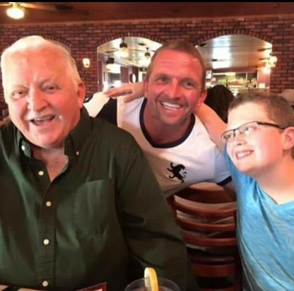 A tree in the middle of a lawn with a concrete curb around it.