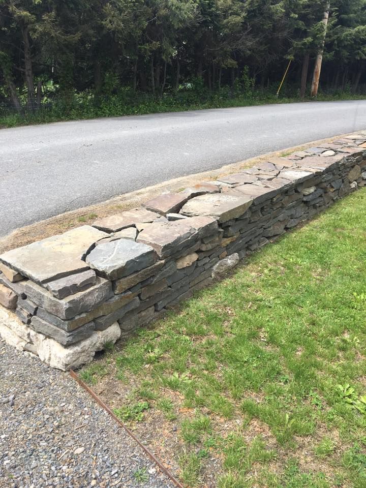 A stone wall along the side of a road next to a road.
