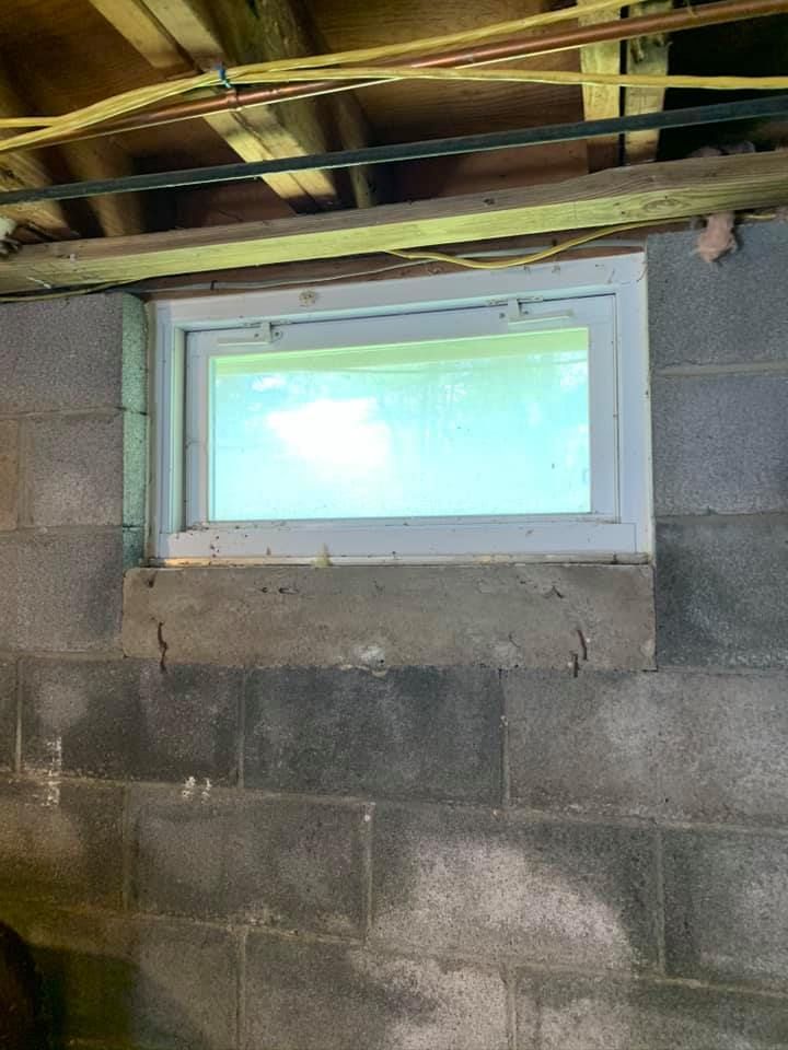 A window in a brick wall in a basement.