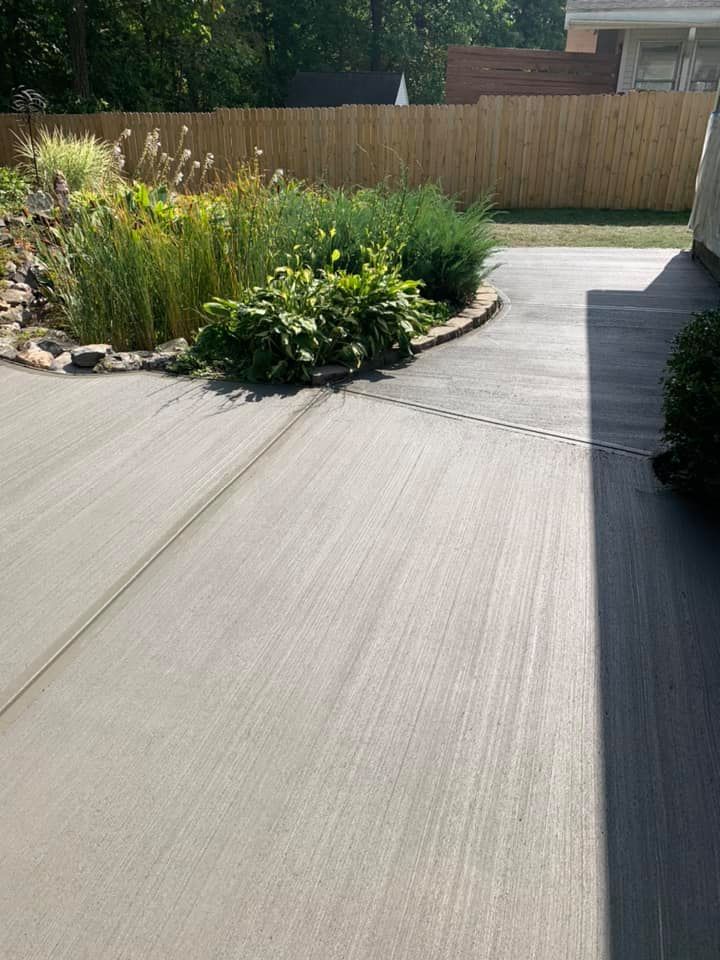 A concrete driveway with a wooden fence in the background.
