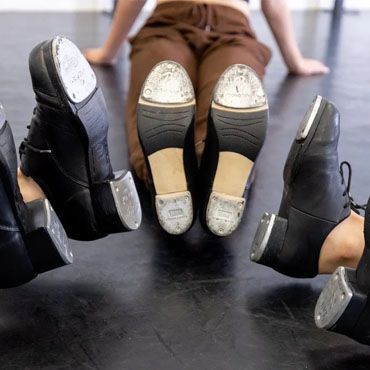 A group of people are sitting on the floor with their feet in their shoes