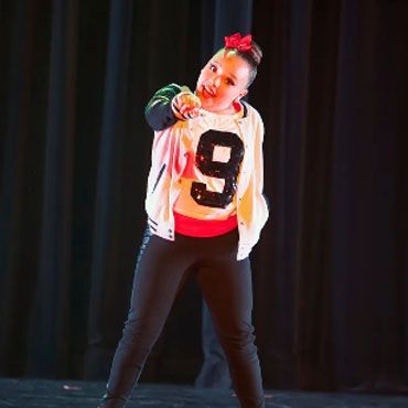 A woman in a pink outfit is dancing on a stage.