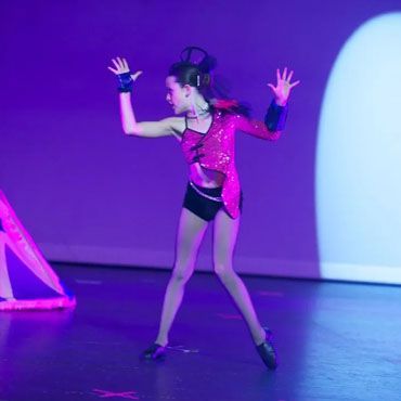 A woman in a pink outfit is dancing on a stage.