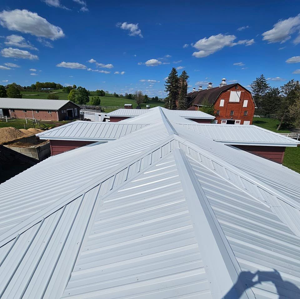 A large white roof with a red barn in the background.
