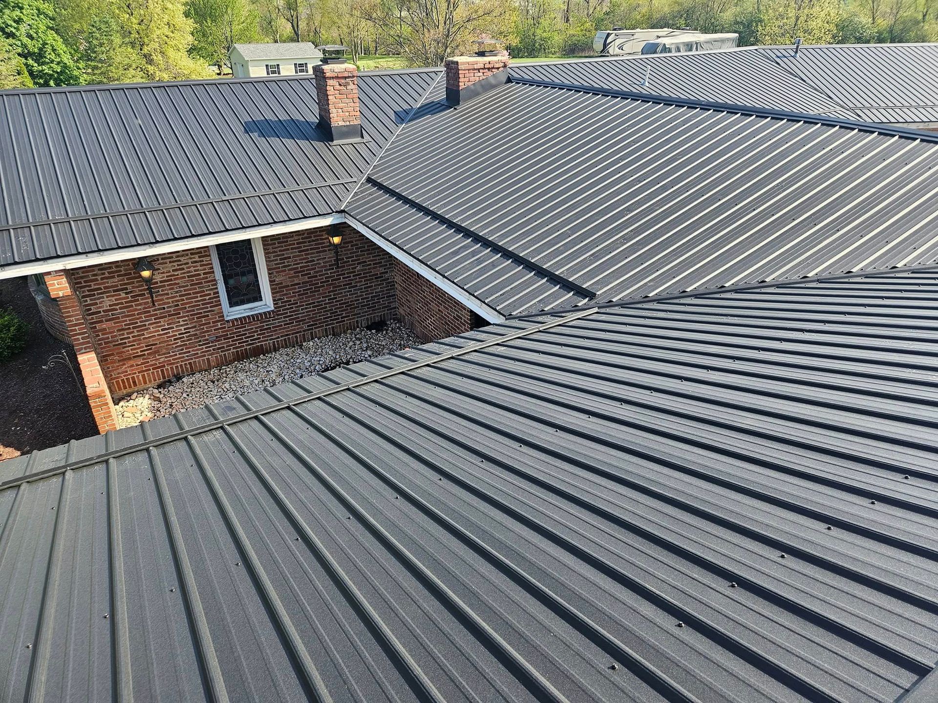A black metal roof is sitting on top of a brick house.