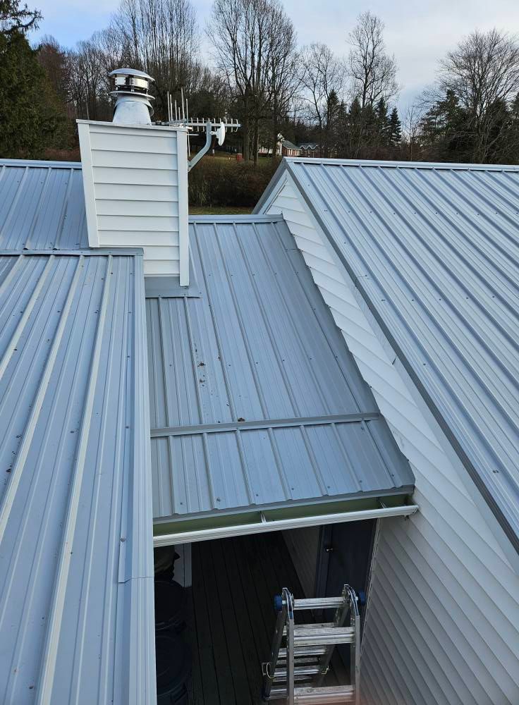 A white house with a metal roof and a chimney
