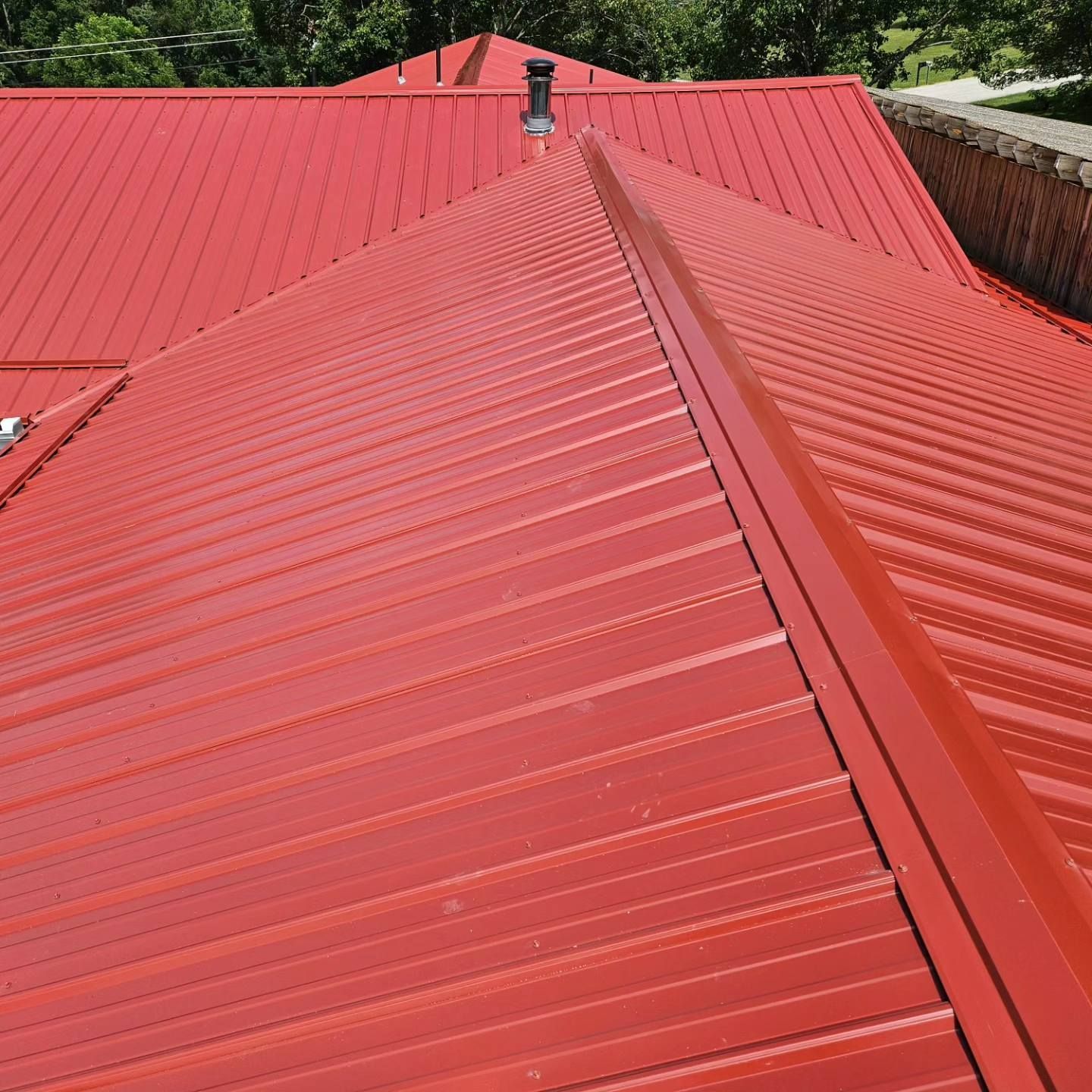 A red metal roof with a chimney on top of it