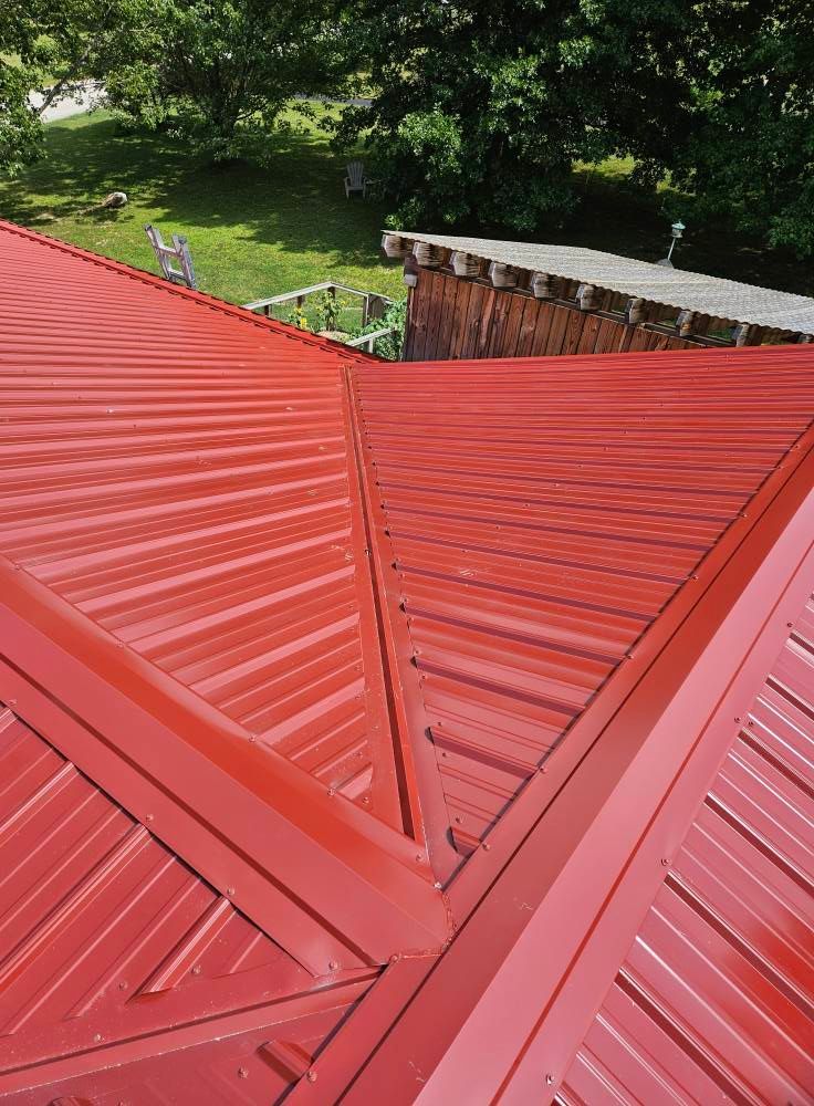 A close up of a red roof with trees in the background.