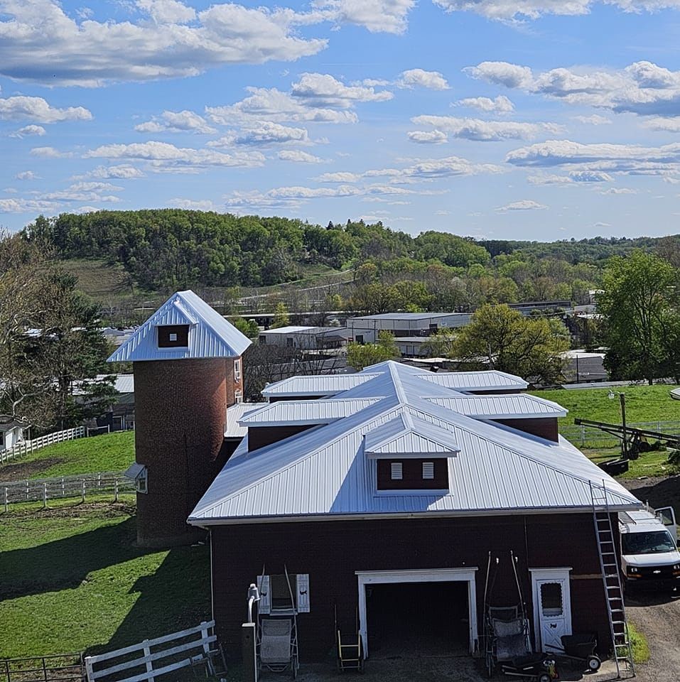 An aerial view of a barn with a silo in the background