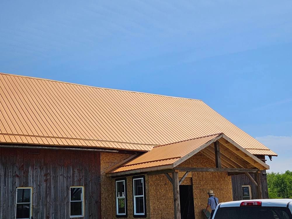 A man is standing in front of a barn with a car parked in front of it.