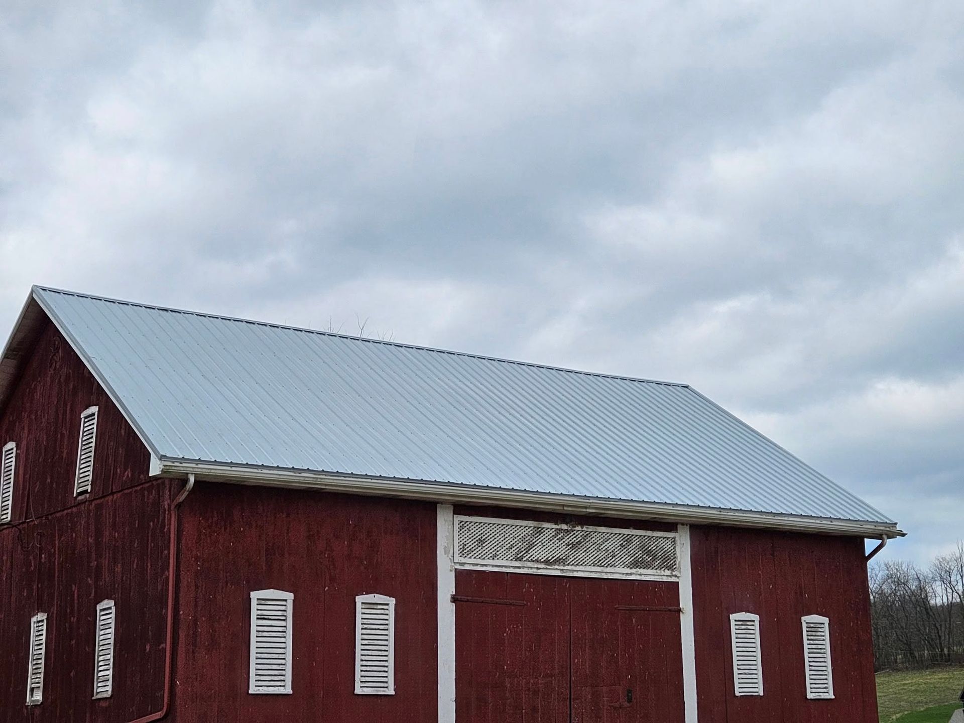 A red barn with a metal roof and white windows